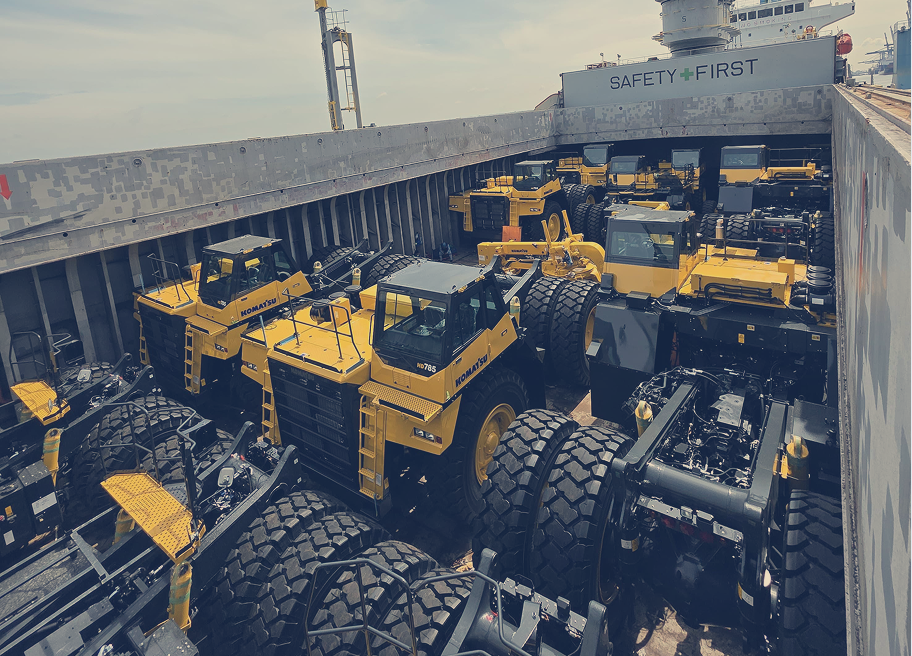 Well-secured Komatsu units inside vessel cargo hold under “Safety First” standards